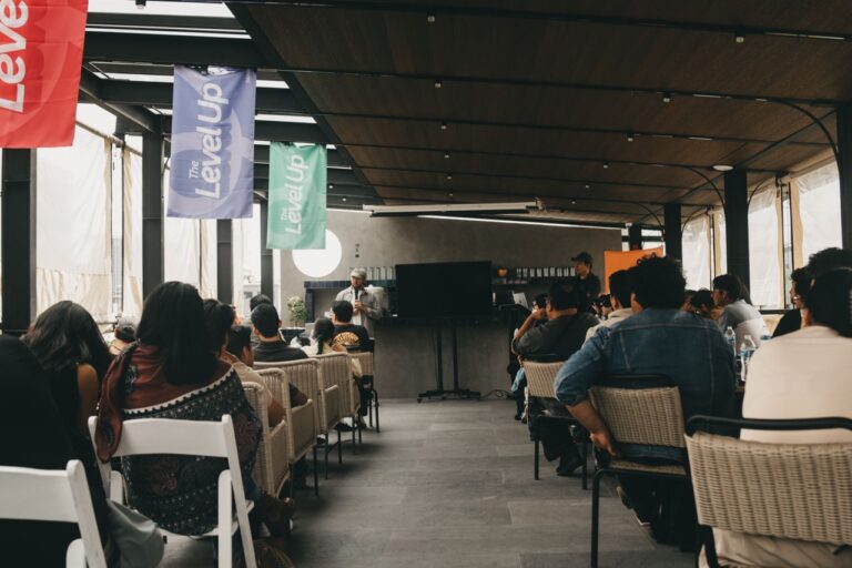 People attending a business conference in a modern indoor setting in Mexico City, featuring banners and a speaker.