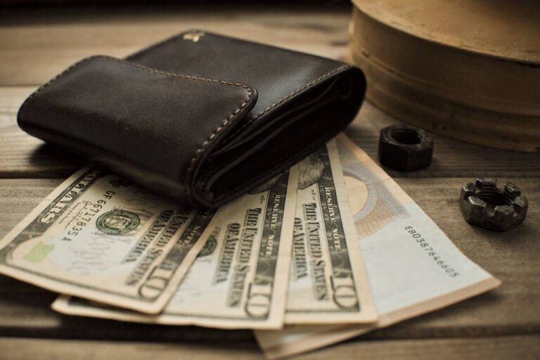 Close-up view of a leather wallet with US dollar bills on a wooden table.
